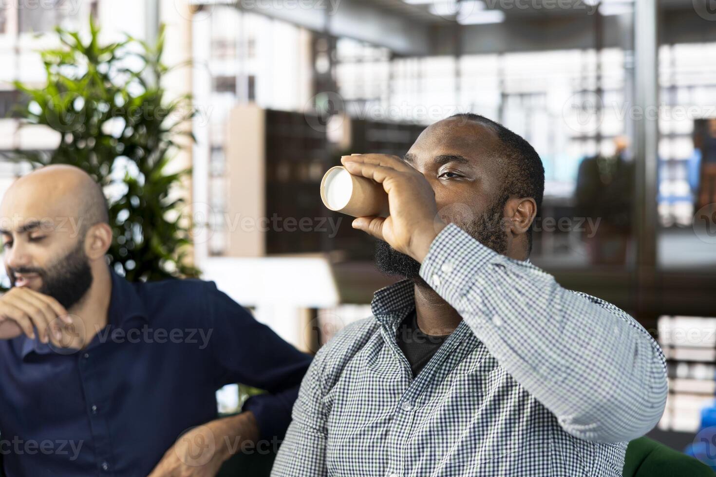African american man drinking coffee during briefing meeting to share new ideas for profit growth. Employee in office enjoying caffeinated beverage while talking with director photo