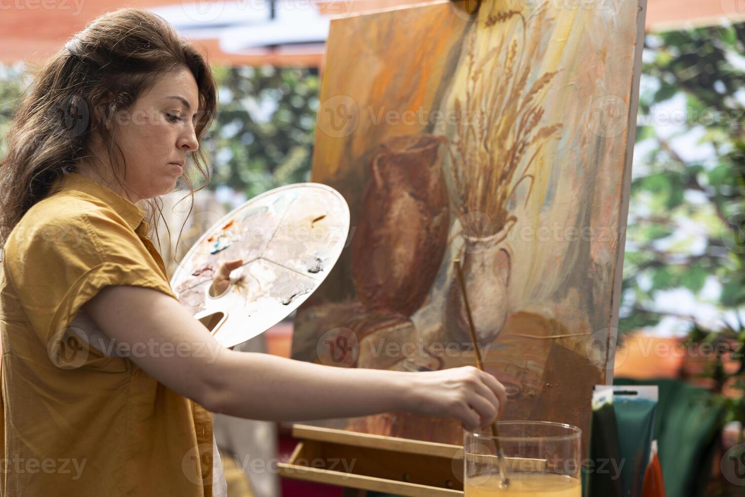 Skilled woman painting an artwork with colorful paints mixed on a palette, creating a beautiful creative paintwork with a certain painting technique in her atelier. Artist mixing watercolor. photo