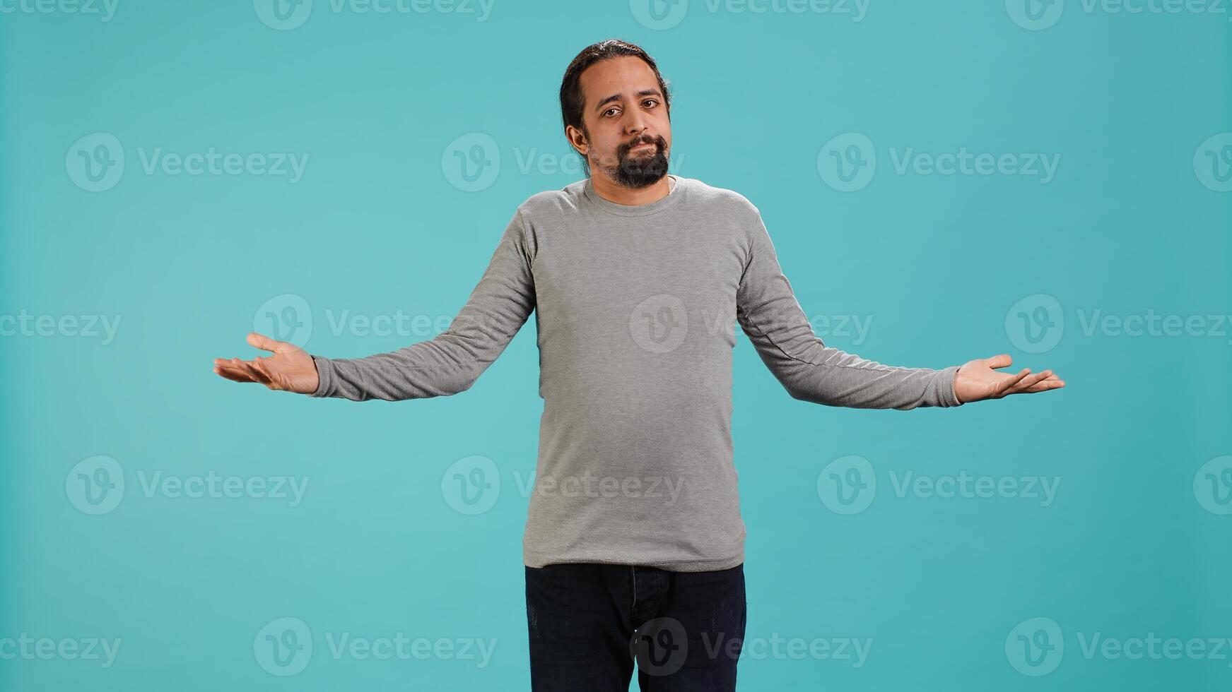 Man shrugging shoulders, expressing uncertainty or helplessness, having troubled facial expression. Person unable to provide assistance to friend, feeling powerless, studio background, camera A photo