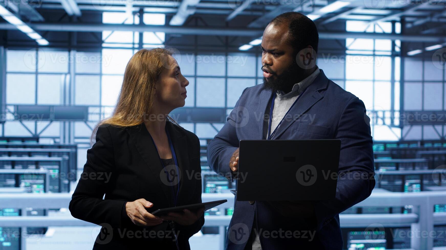 African american admin greeting inspector arriving in data center to supervise operations. IT expert in server hub workspace doing hand shake with supervisor monitoring performance, camera A photo