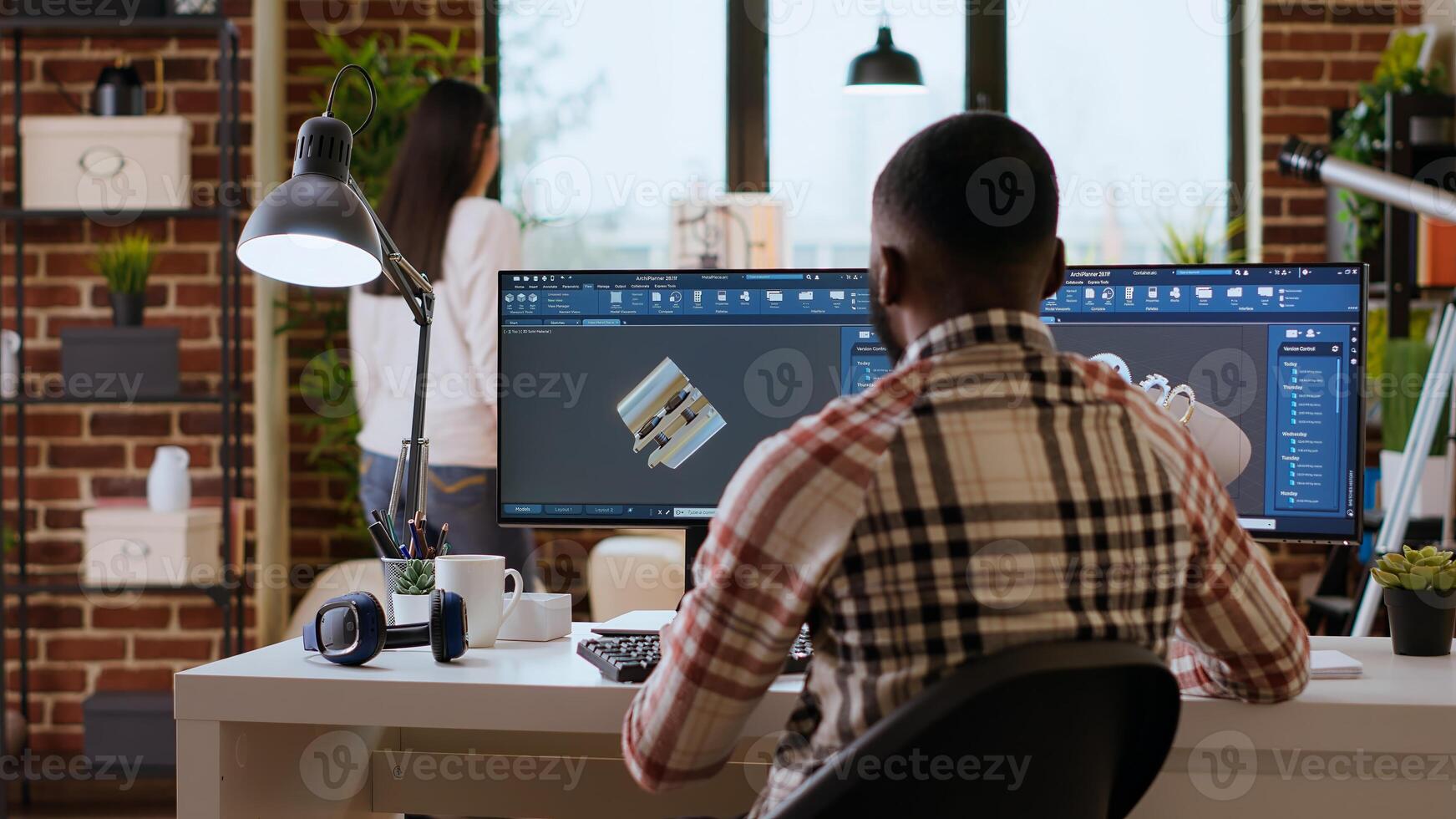 Engineer designs a turbine in an industrial office using CAD software. Working from home with dual monitors and tools for 3D rendering, boosting productivity and technical precision. Camera B. photo
