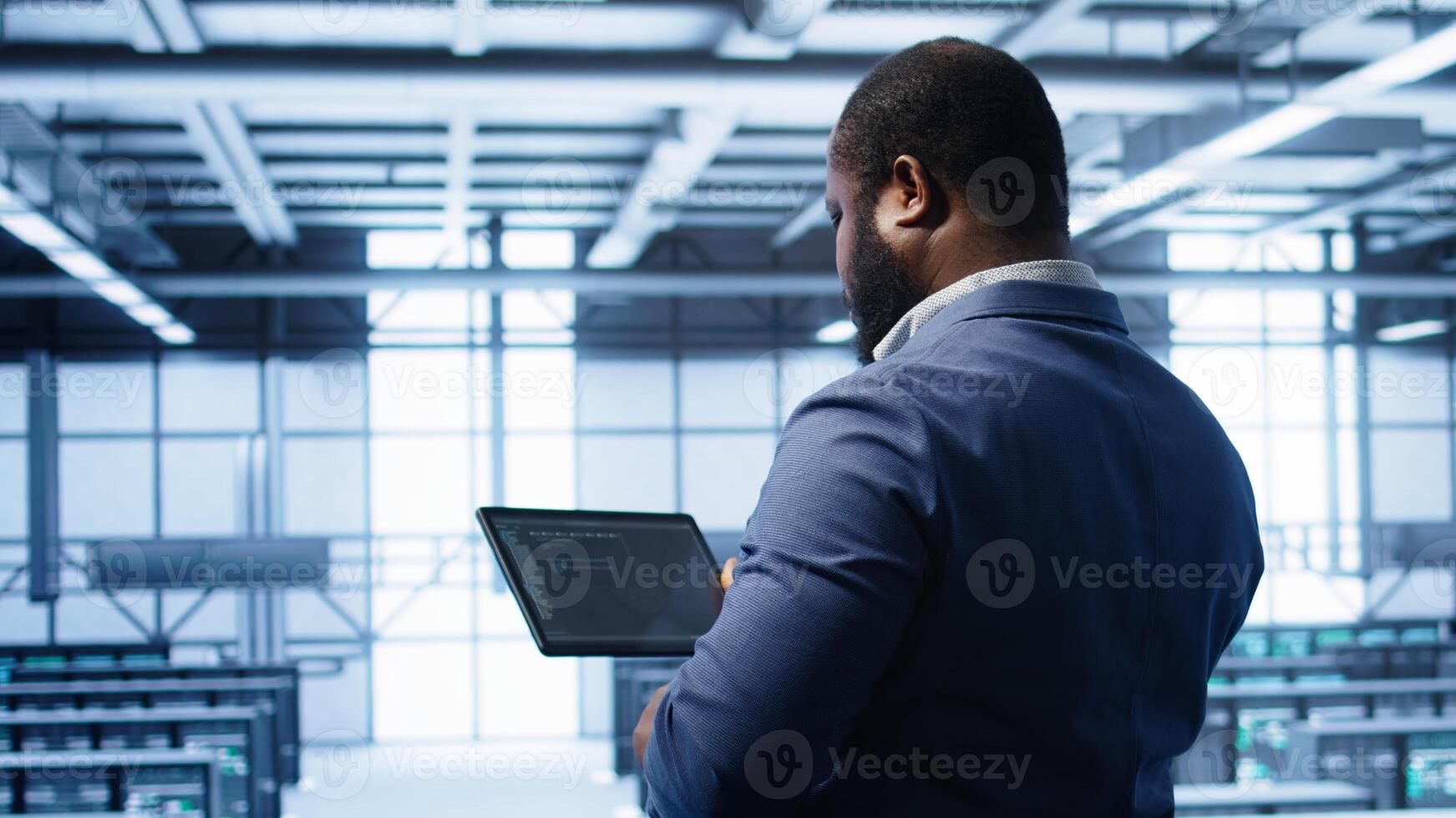 IT operator in server room workspace using tablet to patch network issues affecting transfer rates. Engineer in data center fixing errors affecting server rows rigs, camera B photo
