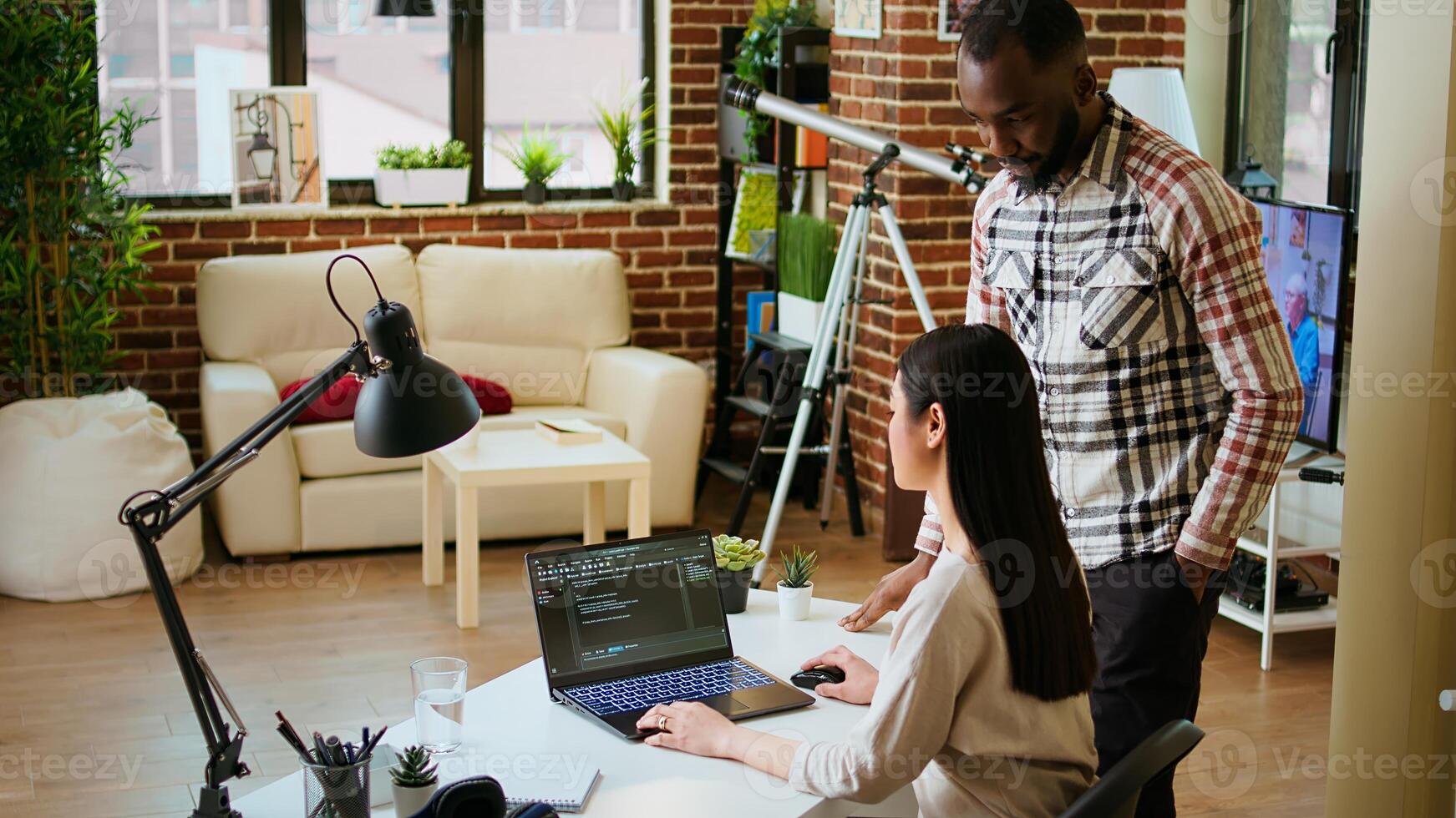 Diverse software developers team coding on a laptop in a cozy home office, working on a new program or app development. Specialists in IT promote programming language and remote tech work. Camera A. photo