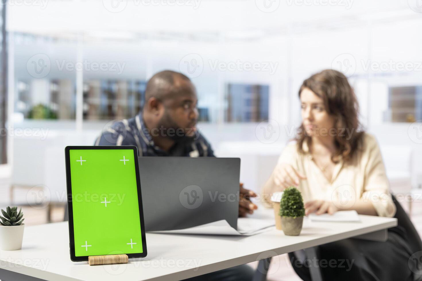 Real estate agent presenting office space layout next to chroma key display, reviewing blueprints with client during an office tour. Businessman negotiating leasing contract terms. photo