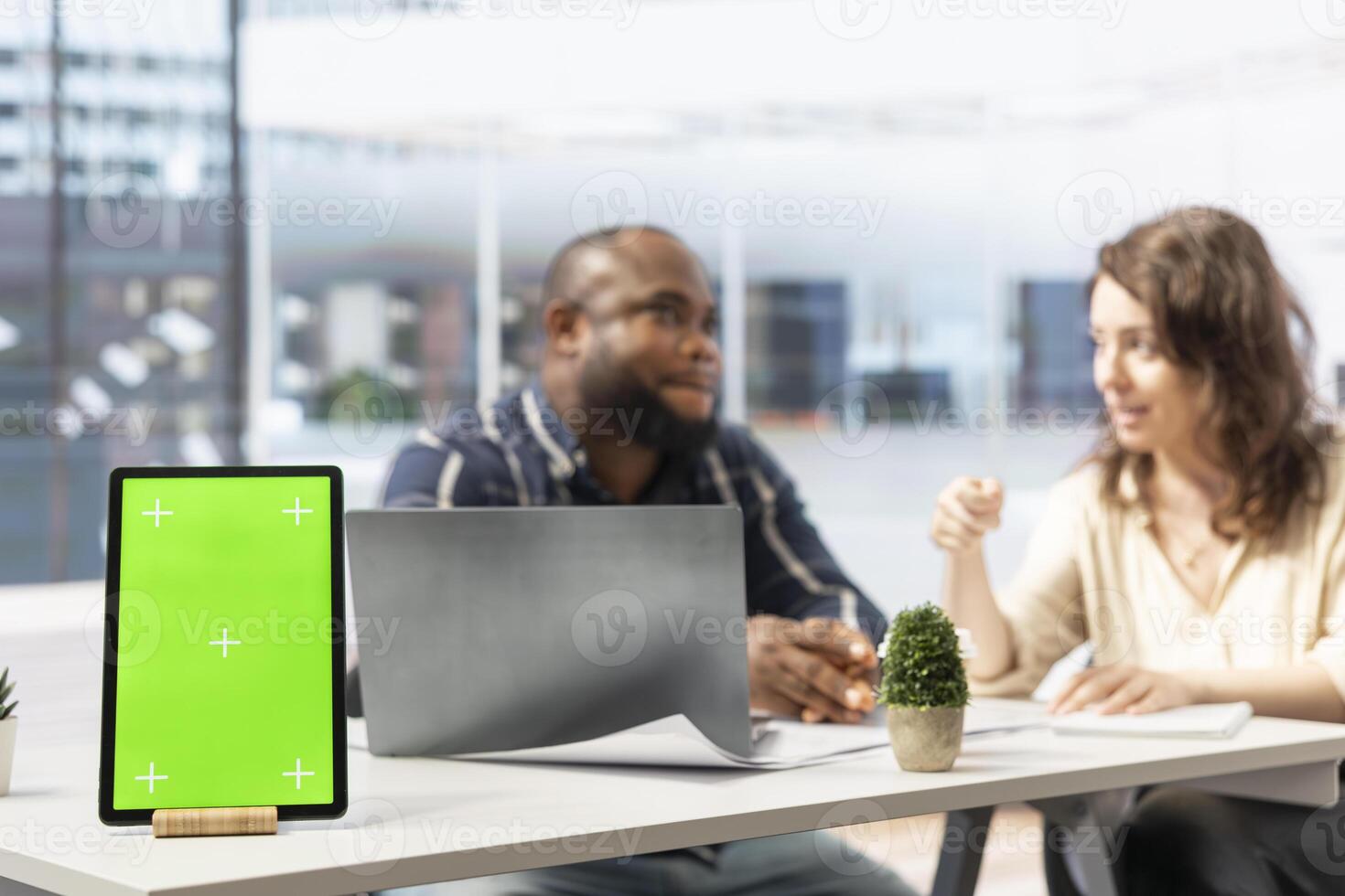 Property realtor showing blueprints to woman next to isolated mockup tablet, discussing leasing contract terms or rental agreement for high class office space. Business relocation plans. photo