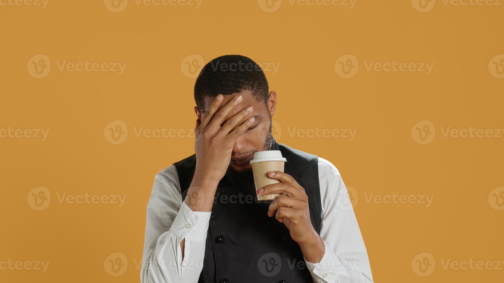 Tired overworked waiter drinking a coffee cup to relax after long shift, working in catering and service oriented environment. Employee feels fatigued and serving caffeine drink. Camera A. photo
