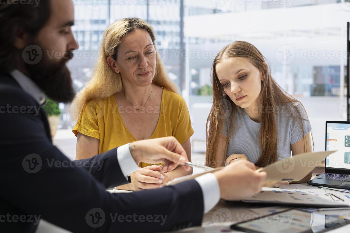 Financial advisor finishing analytic report on investment performance, showing it to clients. Agent presenting portfolio economic evolution to parent and teenager in office photo