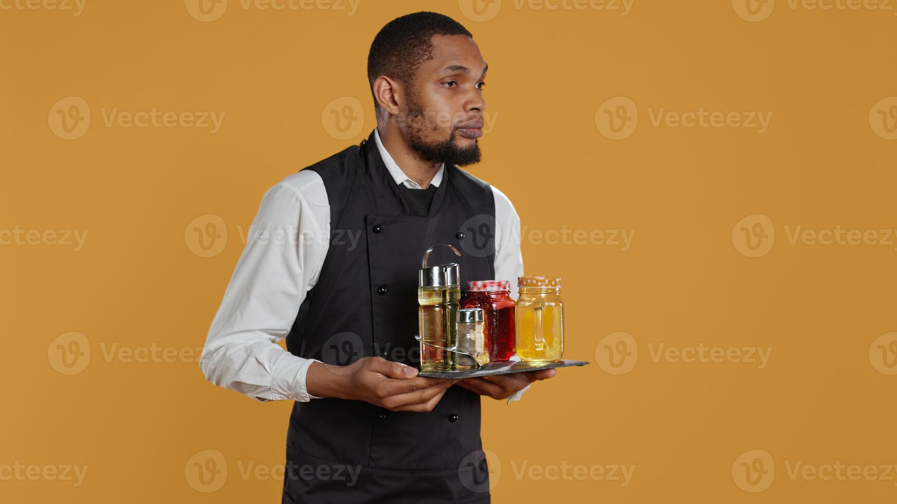Waiter bringing drinks in glasses on a tray for clients at a table, serving lemonade to customers before their dinner. Professional staff serving people at a five star restaurant. Camera B. photo