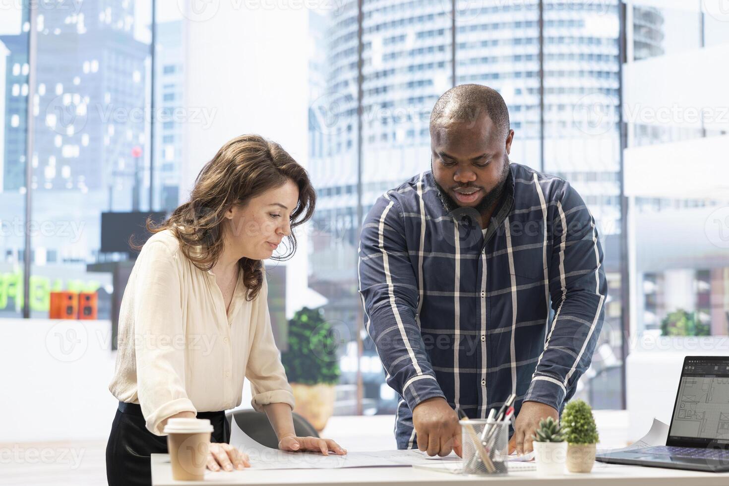 Realtor helping client to choose an office space in high class modern building, entrepreneur planning a relocation. People studying the architectural blueprints to present the property potential. photo