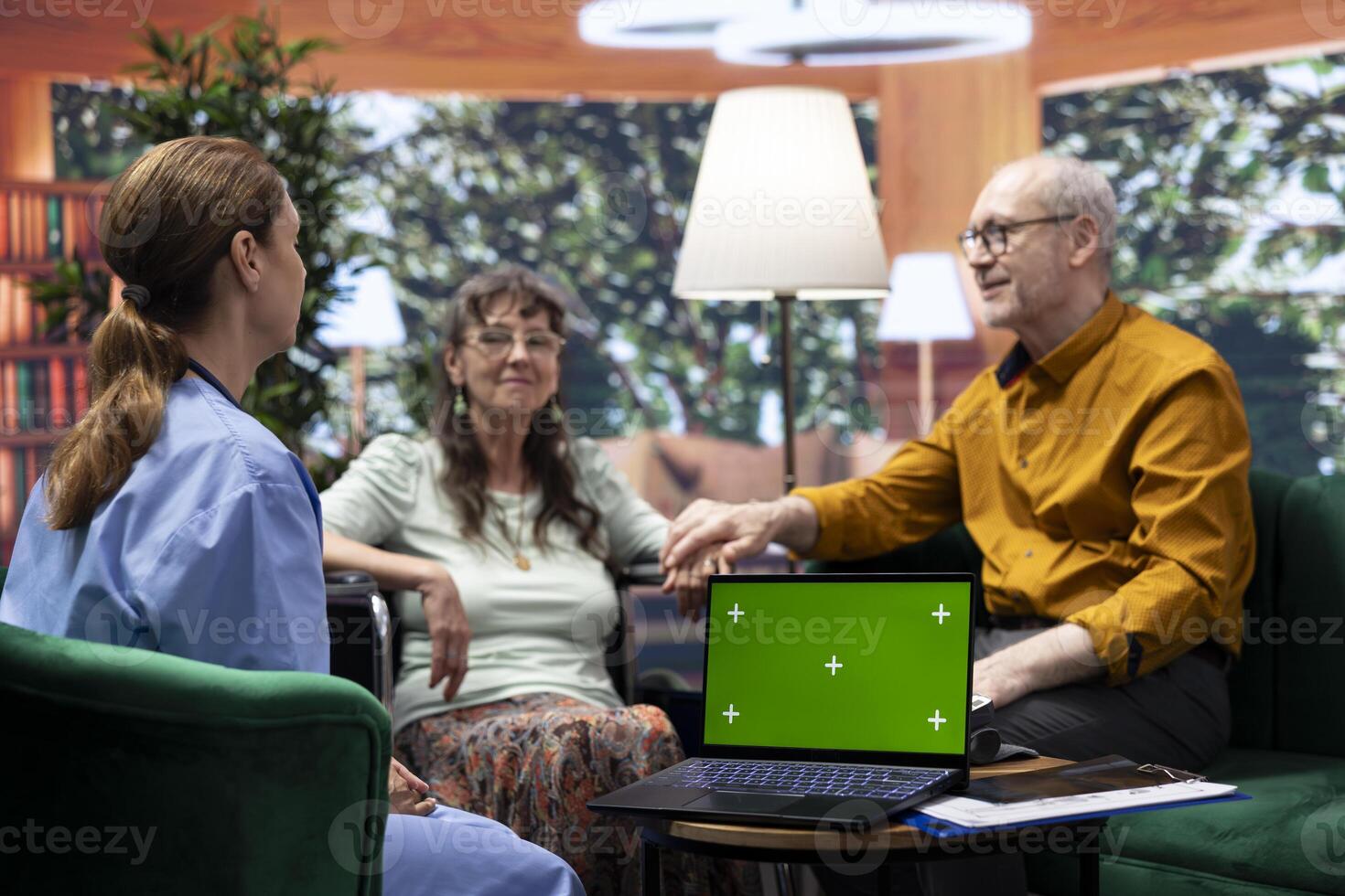 Senior woman with disability asking nurse for advice and medicine, doing consultation at home next to chroma key copy space screen. Old patients discussing about treatment for recovery. photo