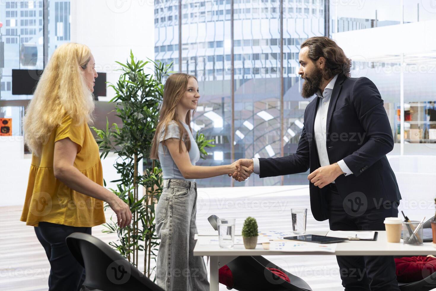 Welcoming financial advisor meeting with clients to recommend financial products and investments, greeting them. Investment strategies expert in workspace doing handshake with customers photo