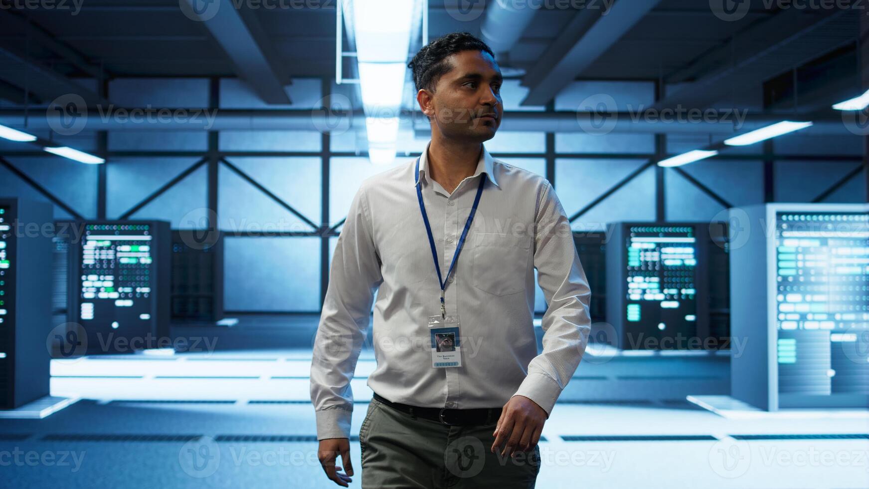 Admin walking amidst server rows, looking to ensure optimal performance and reliability by implement and managing gear. IT staff member in data center overseeing high tech facility, camera B photo
