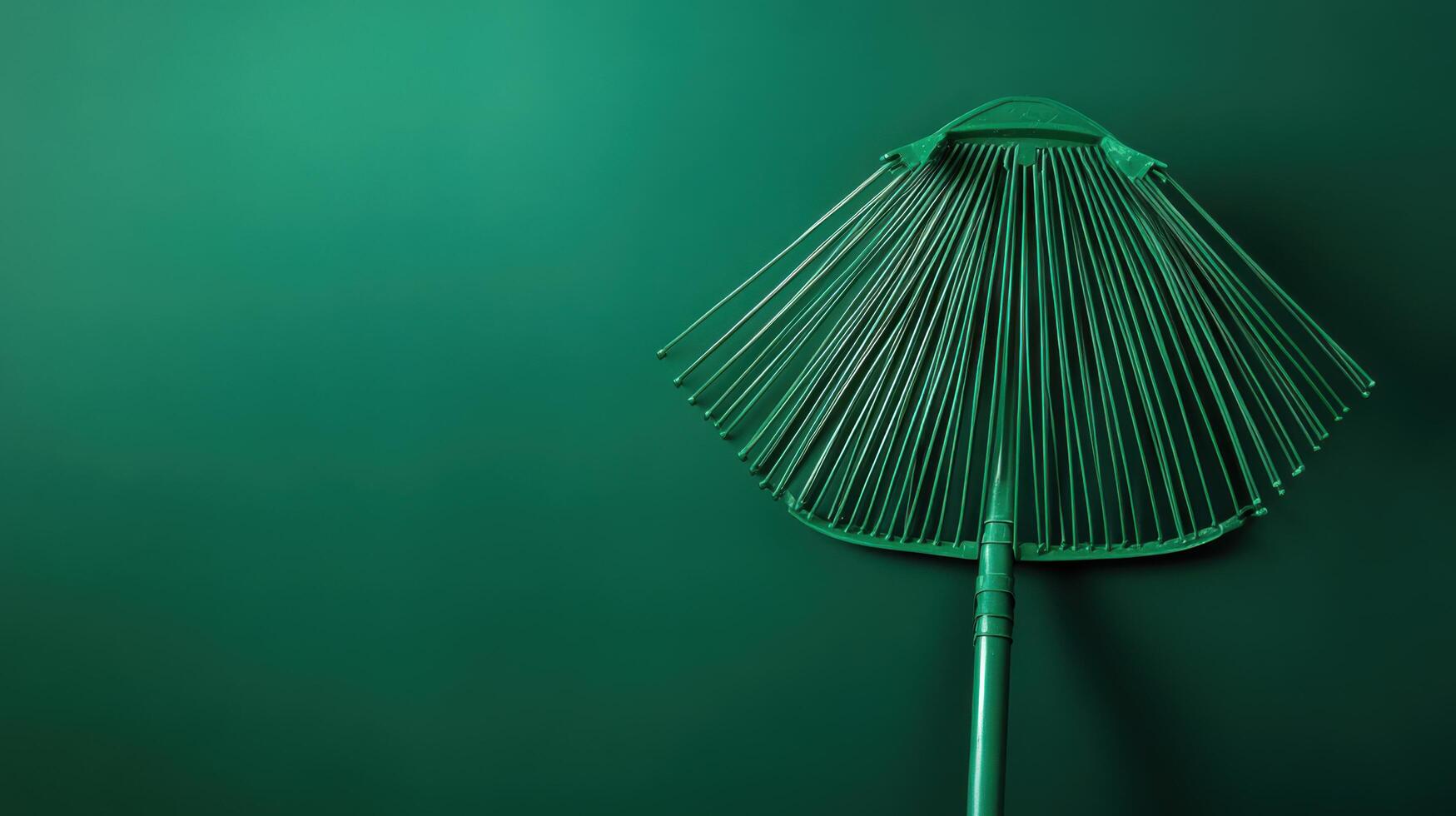Green garden rake against a dark background with a smooth surface reflecting light from above photo