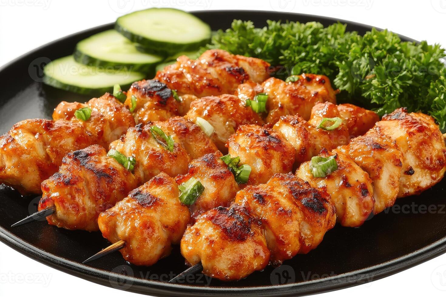 Grilled chicken skewers with garnish on black plate photo