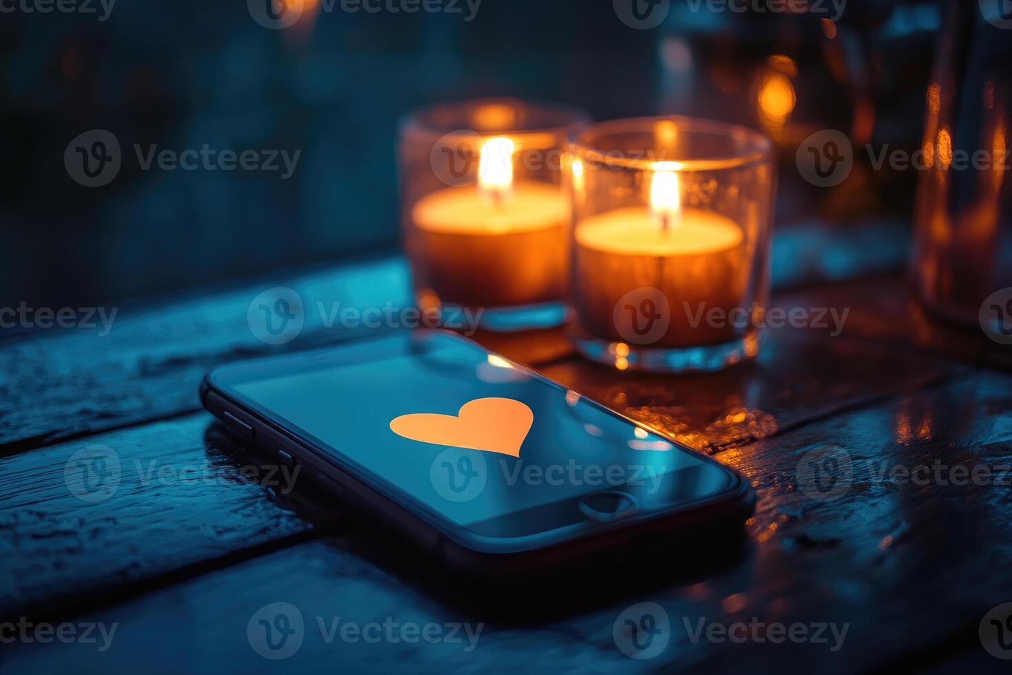 Smartphone showing heart symbol on screen by candlelight on wooden table photo