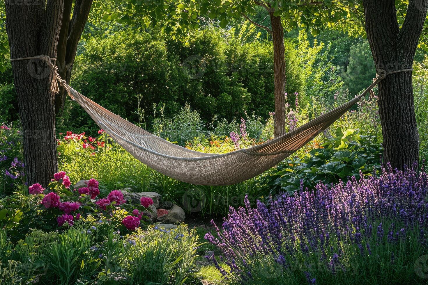 Relaxing hammock hanging between two trees in lush garden. photo