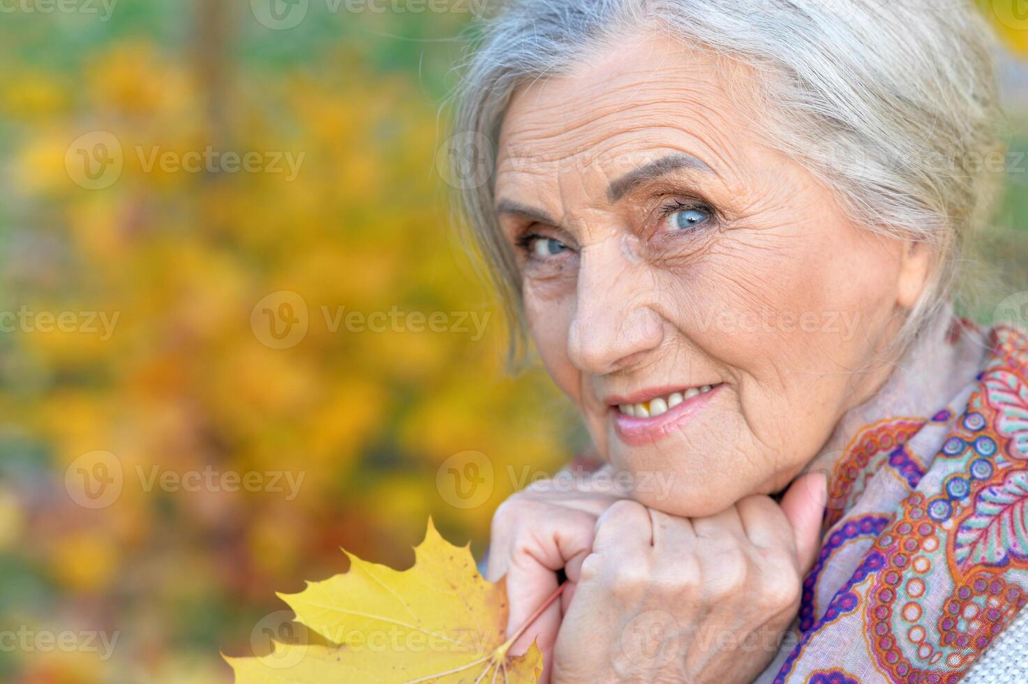 Senior nice woman walking in the park in autumn. photo