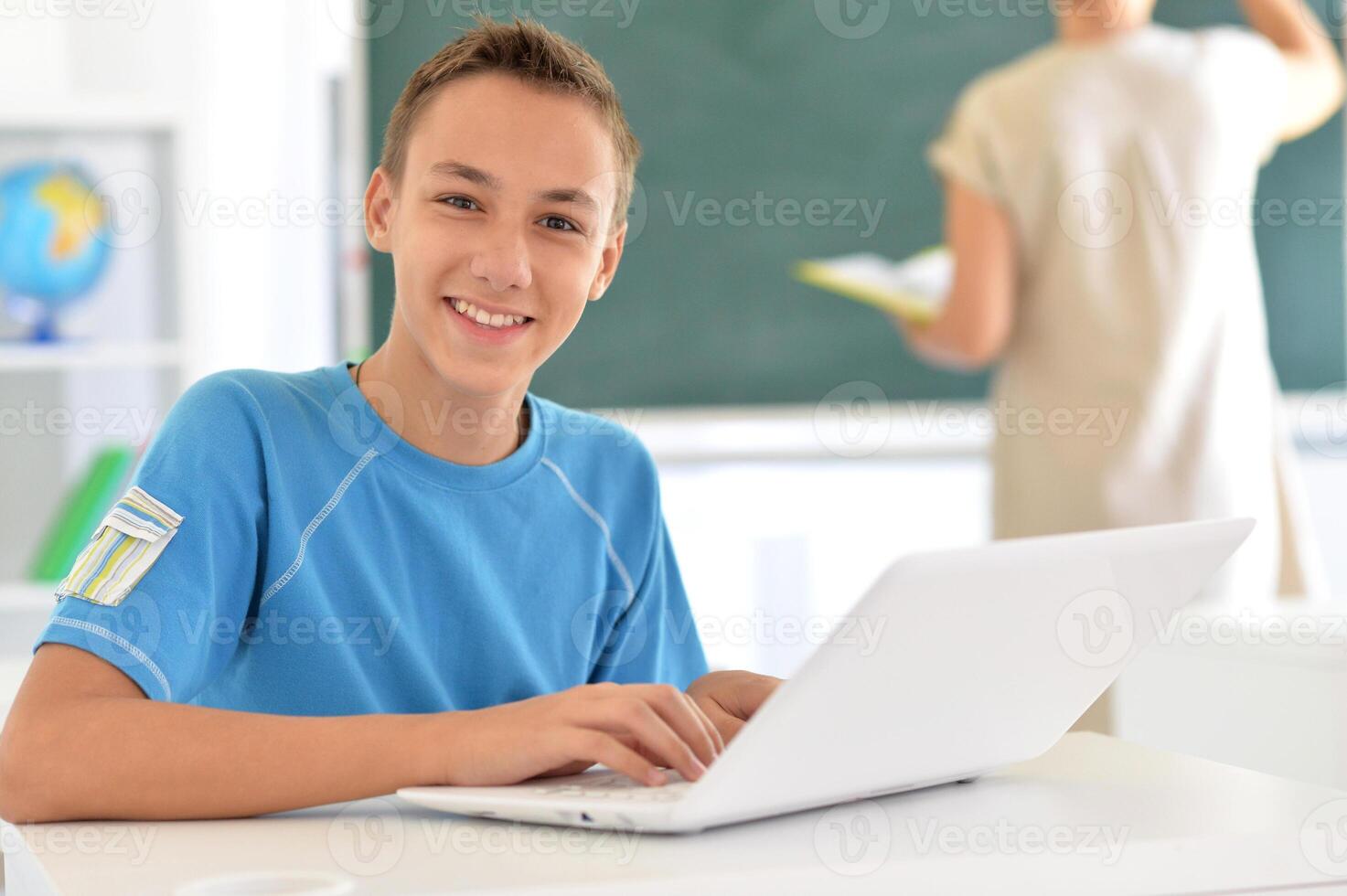 Portrait of boy studing with laptop at classroom photo