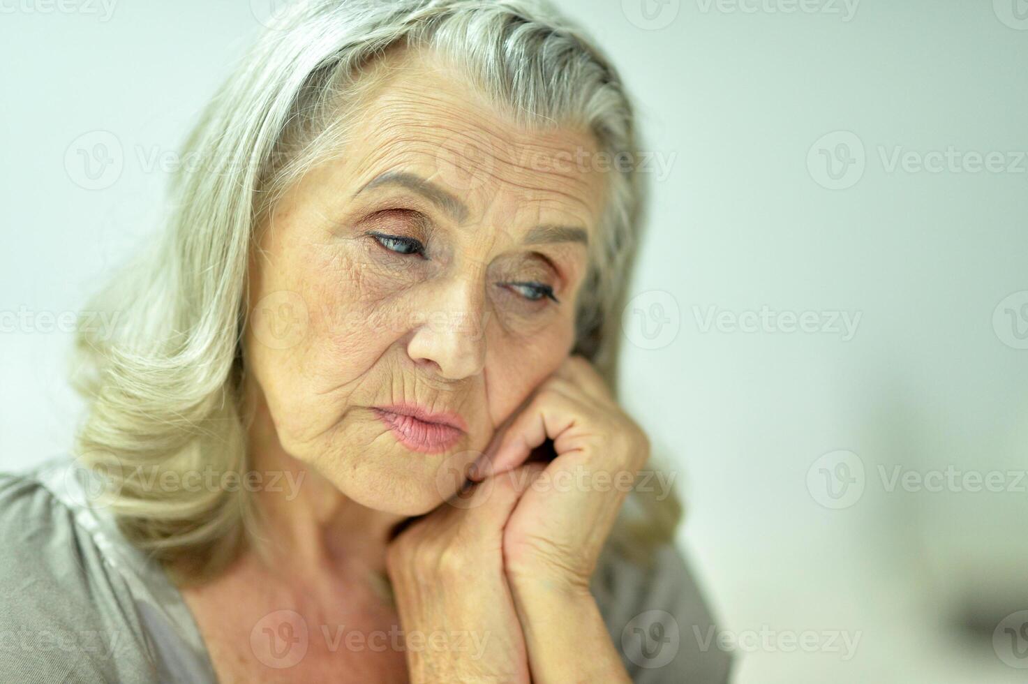 Portrait of a sad elderly woman posing at home photo