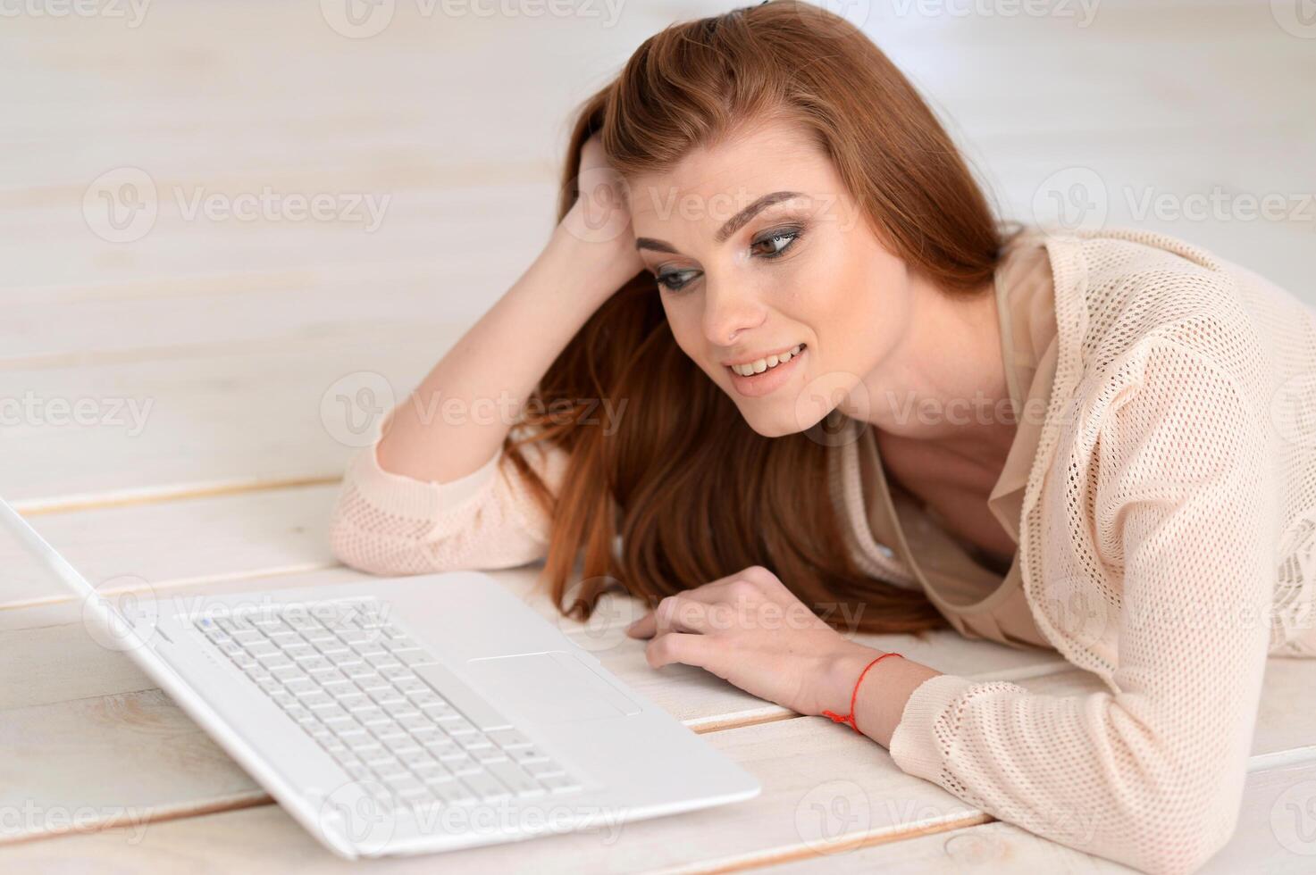 Adult beautiful woman lying on floor with laptop photo