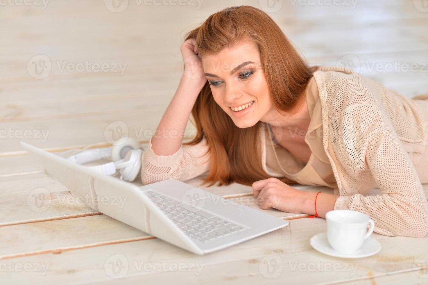 Adult beautiful woman lying on floor with laptop photo