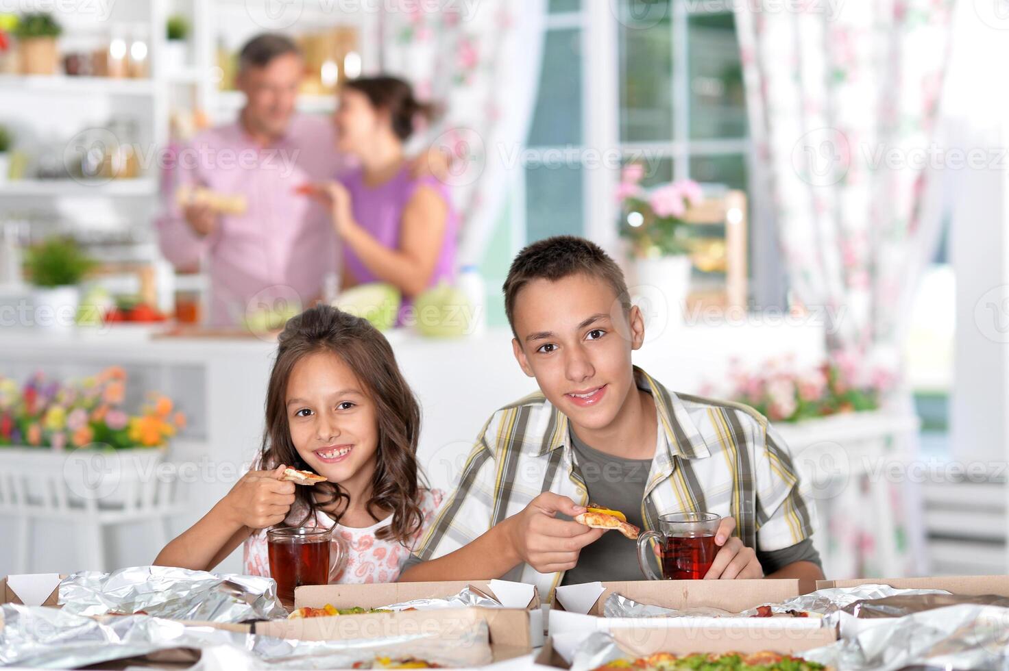Brother and sister having pizza at home photo