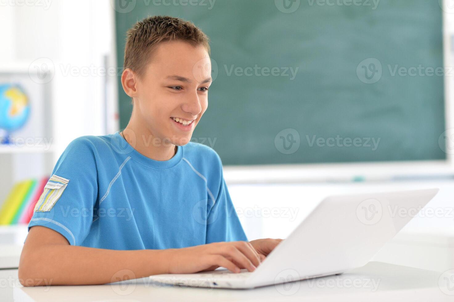 Portrait of boy studing with laptop at classroom photo