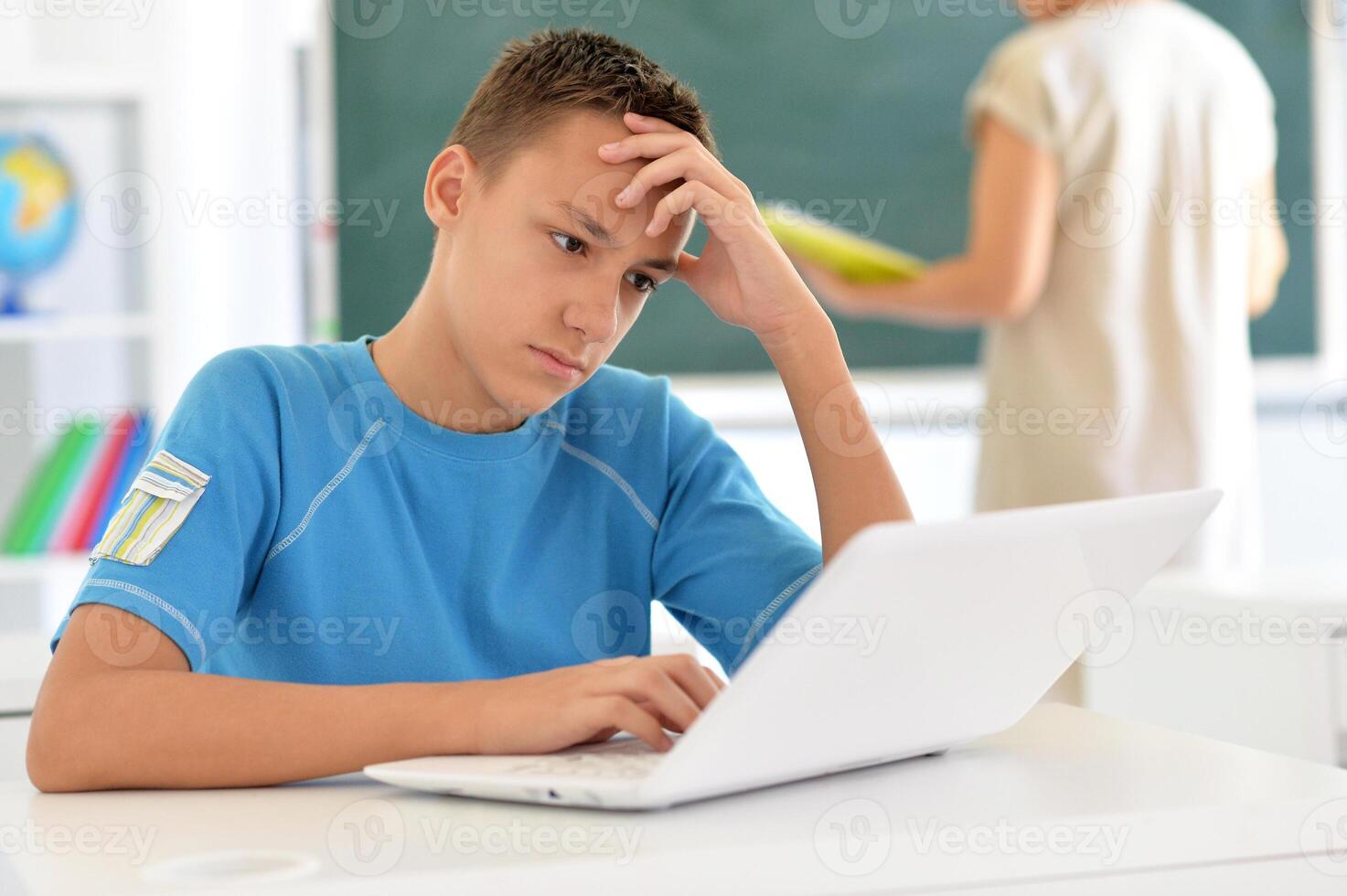 Portrait of boy studing with laptop at classroom photo