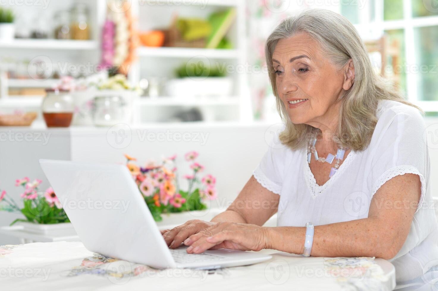 Cute nice senior woman using laptop at home photo