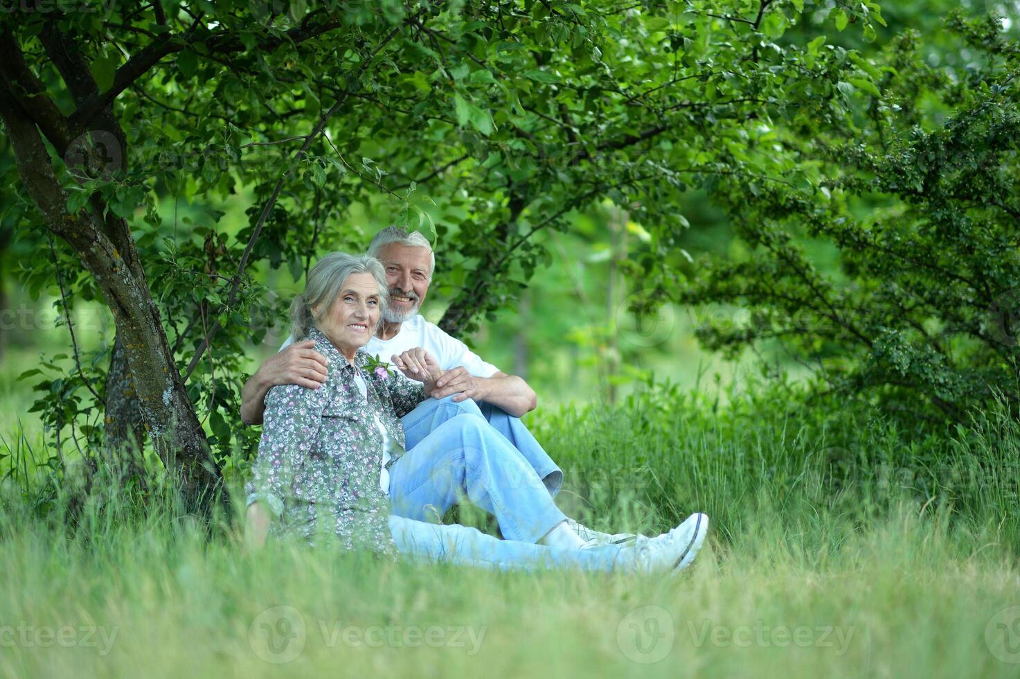 Portrait of senior couple sitting on the grass in the park photo
