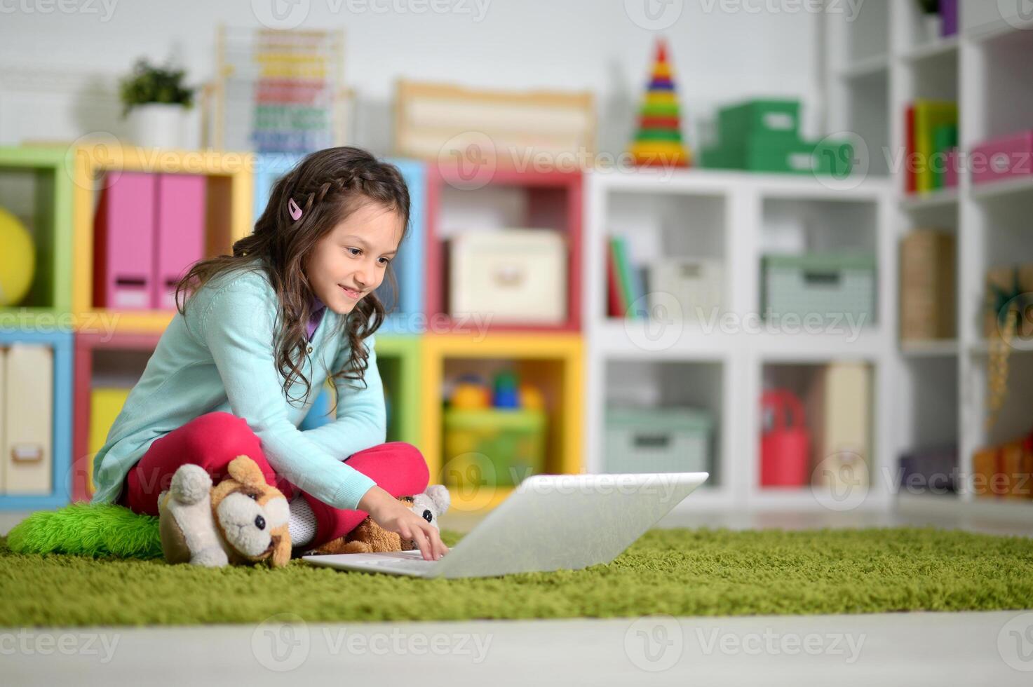 Portrait of cute little girl using laptop photo