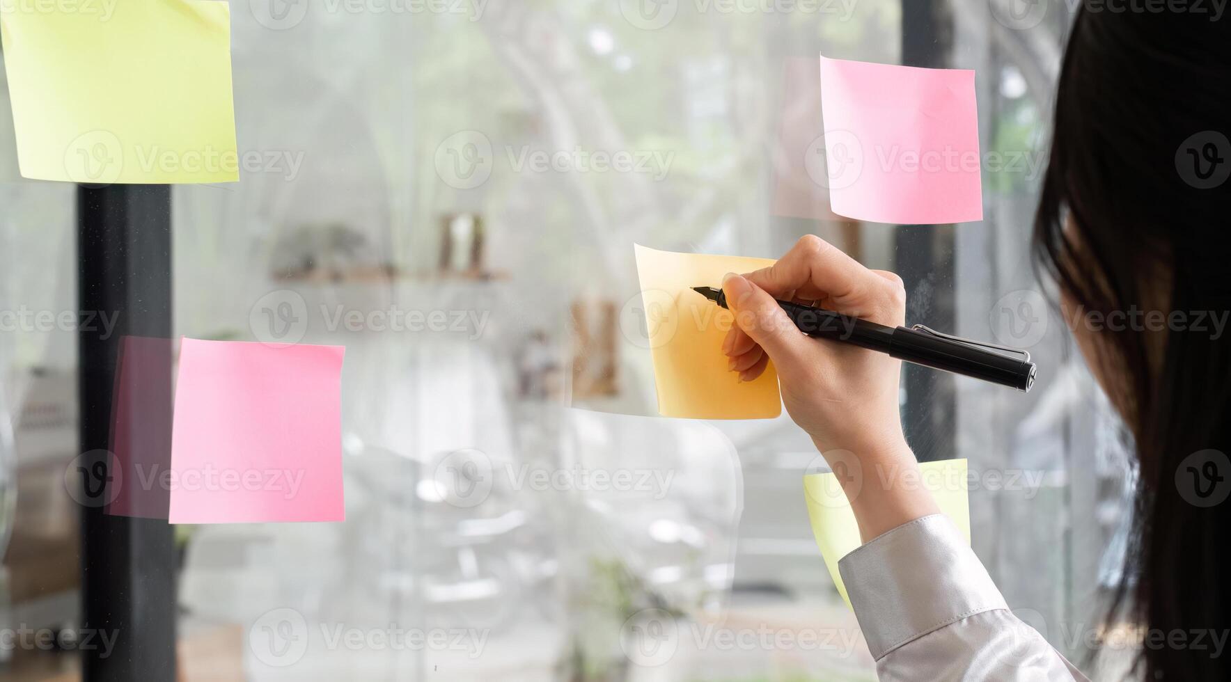 Business woman writes a work plan and plans work on note paper posted on the wall. photo