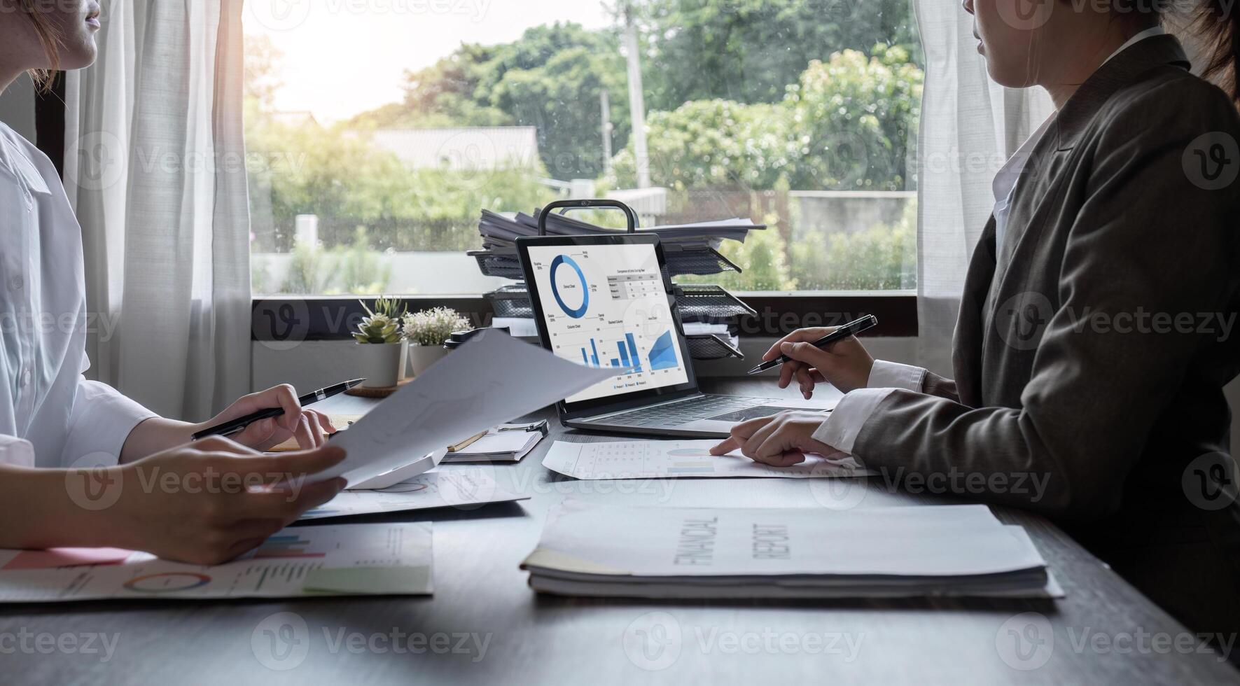 Close-up, A team of accountants and businesswomen sit and work on numbers and graphs. On the laptop on the table in the office photo