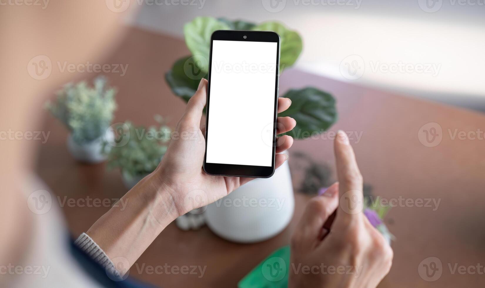 Simulated image of a blank white screen mobile phone Woman using mobile phone on table at home photo