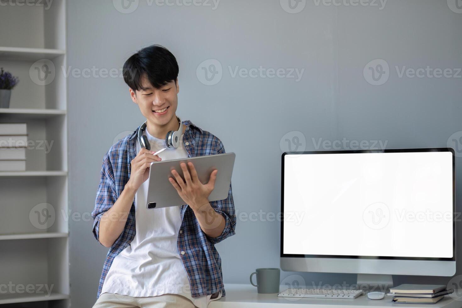 Young Asian student smiling happily at computer with blank screen on table photo
