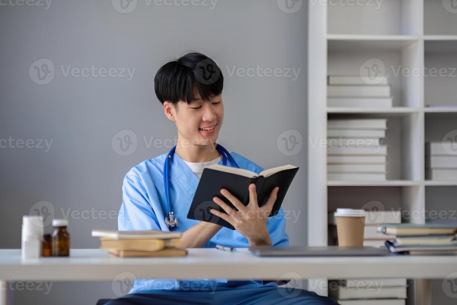 A male medical student sits and reads a book in the library to prepare for a research exam for a medical subject. photo