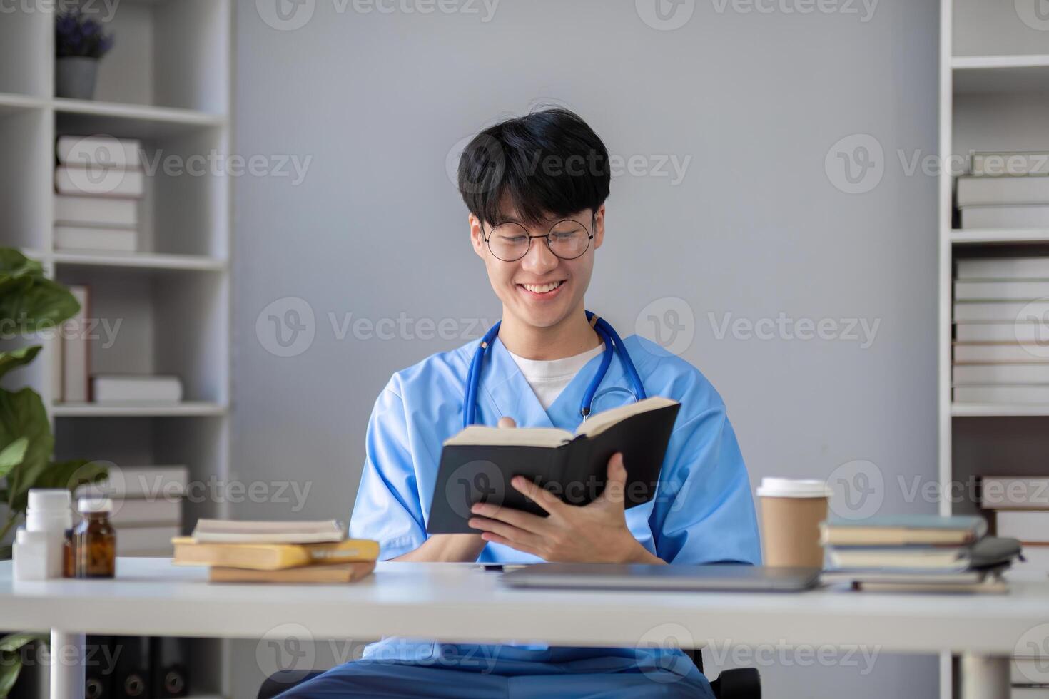 A male medical student sits and reads a book in the library to prepare for a research exam for a medical subject. photo