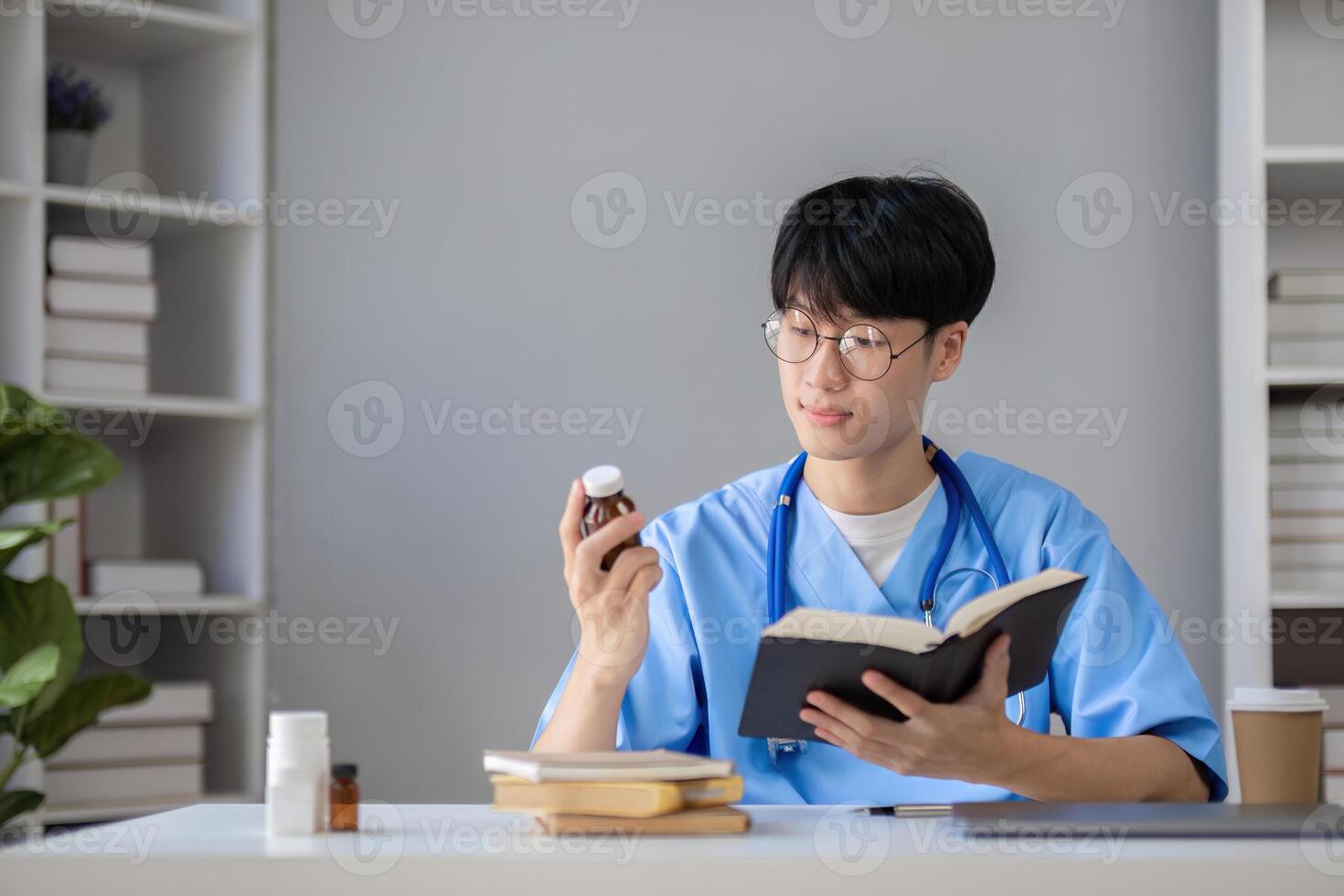 A male medical student sits and reads a book in the library to prepare for a research exam for a medical subject. photo
