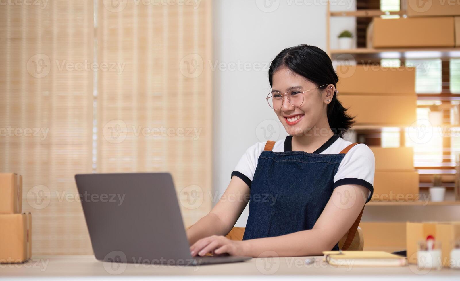 A young Asian entrepreneur sells product online through an online platform and pack product into shipping boxes. photo