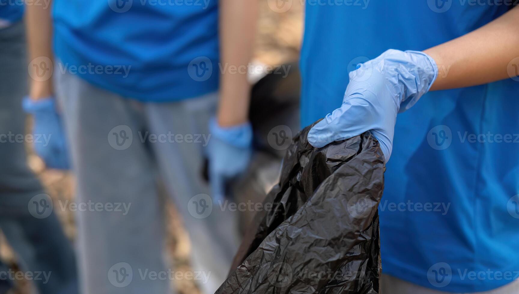 A group of Asian volunteers collects trash in plastic bags and cleaning areas in the forest to preserve the natural ecosystem. photo