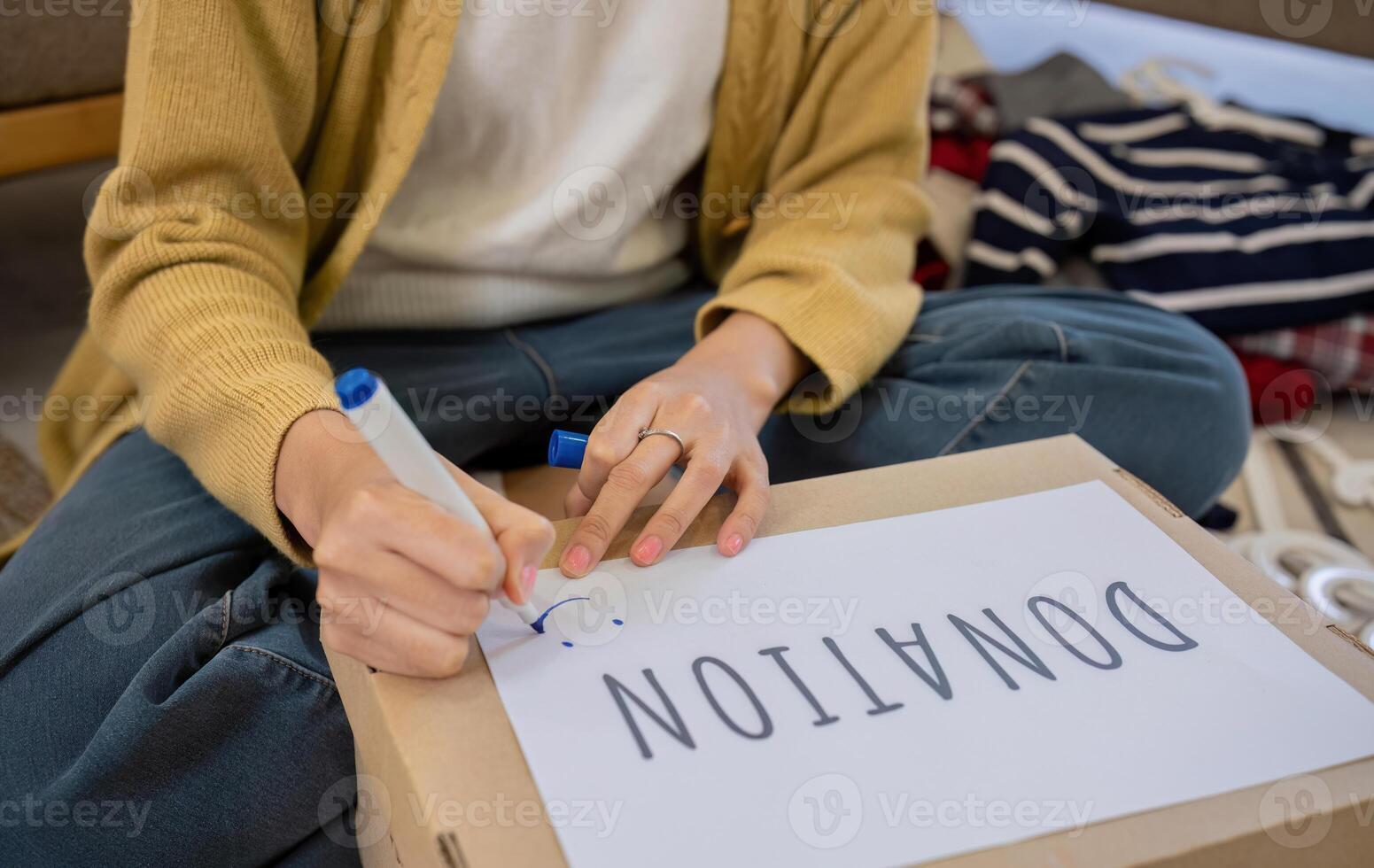 A beautiful Asian woman uses a magic marker to write on a box of clothes that will be donated to show moral support. photo