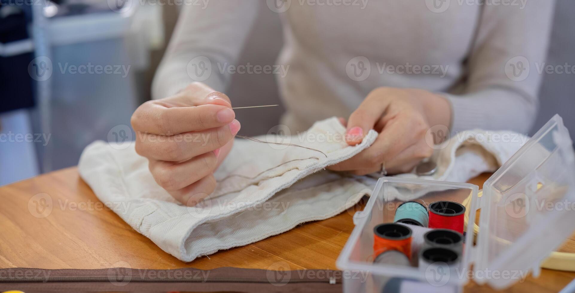 beautiful young woman sewing Repair damaged clothes so that it can be reused. In order to reduce the creation of waste and reduce environmental pollution. photo