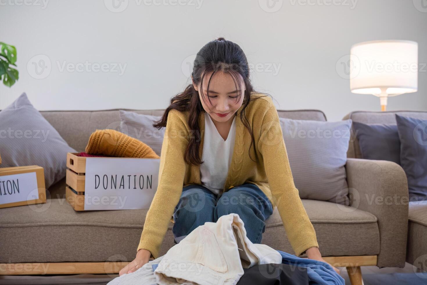 A young woman separates unused clothes and prepares them for donation or recycling in order to reduce air pollution and protect the environment. photo