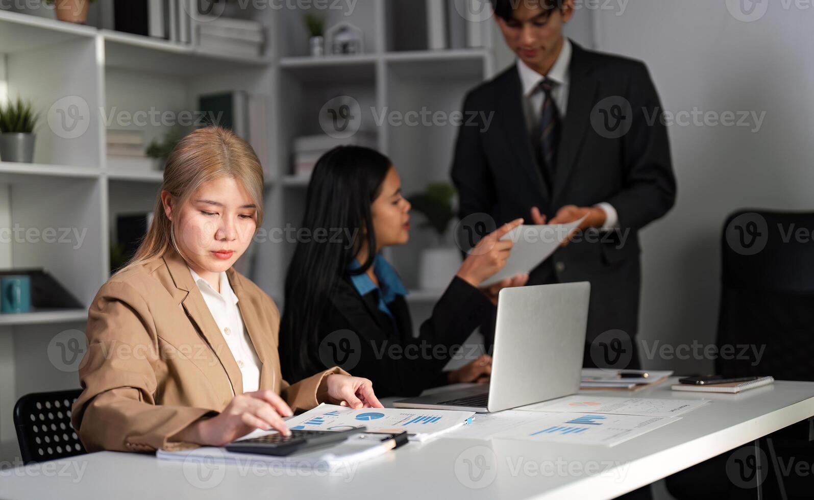 Diverse Business Team Collaborating on Work Plans in Modern Office Setting with Laptops and Documents photo
