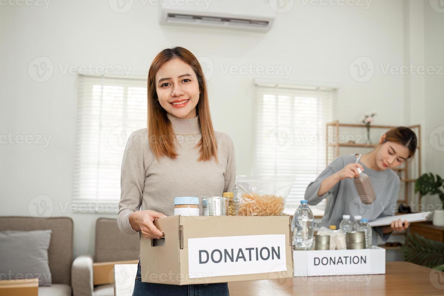 Beautiful female volunteer holds a donation box with canned food in it. photo