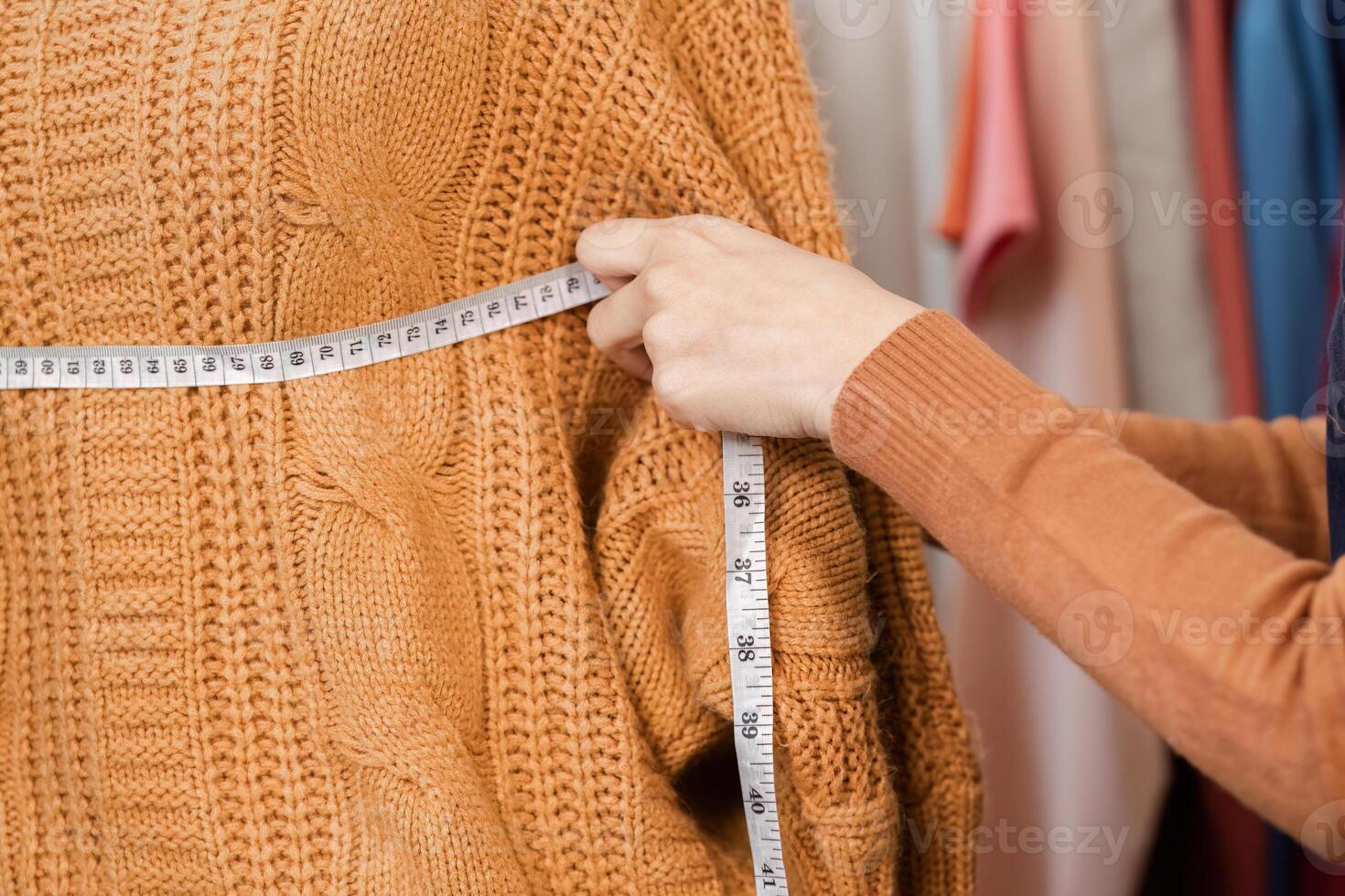 Fashion designer measuring a knitted sweater for precise tailoring in a boutique environment photo