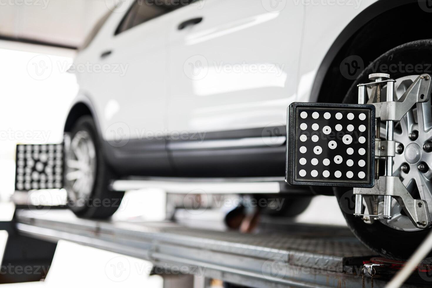 Modern car wheel undergoing alignment on lift in garage photo