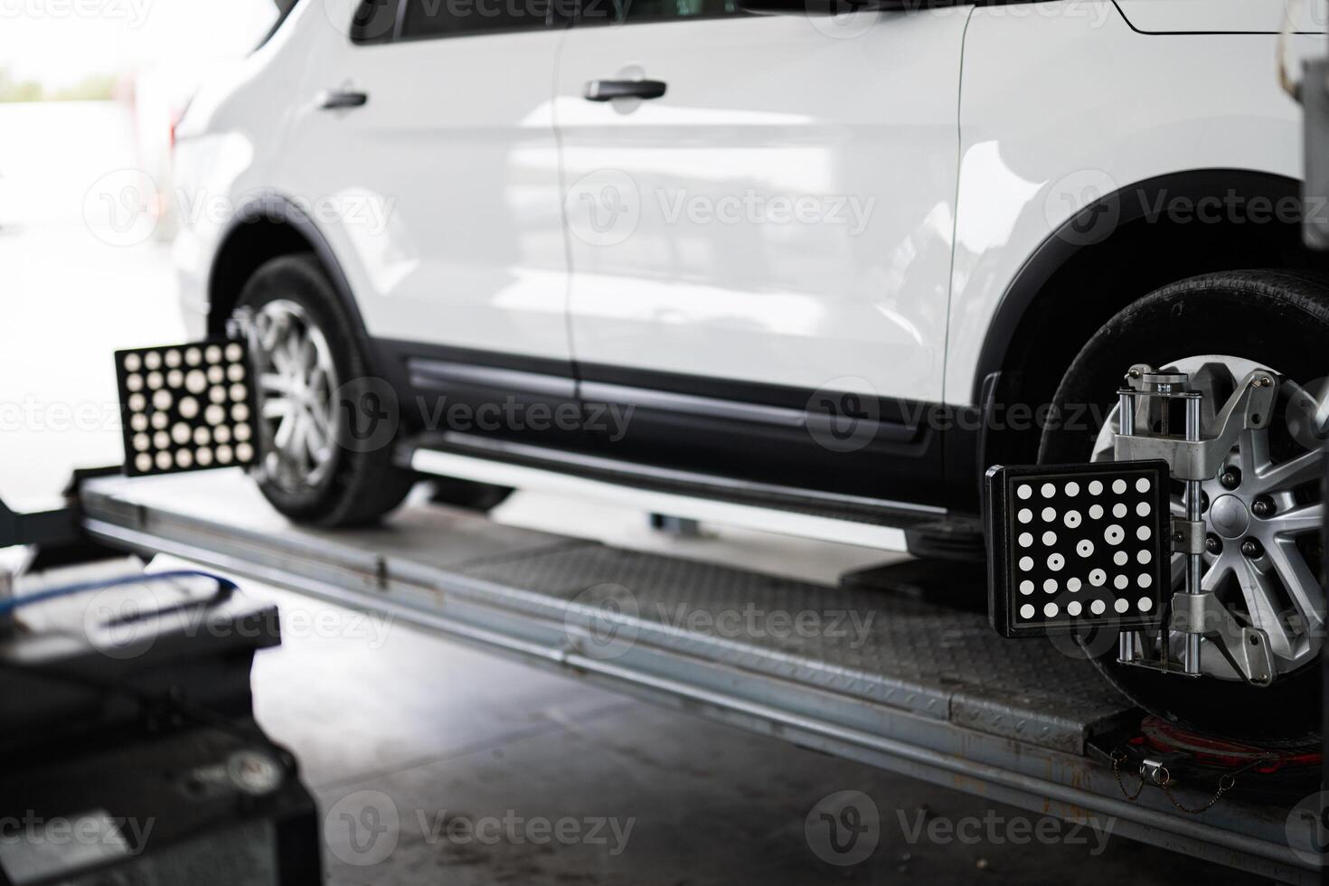 Car on lift for wheel alignment service in auto shop photo