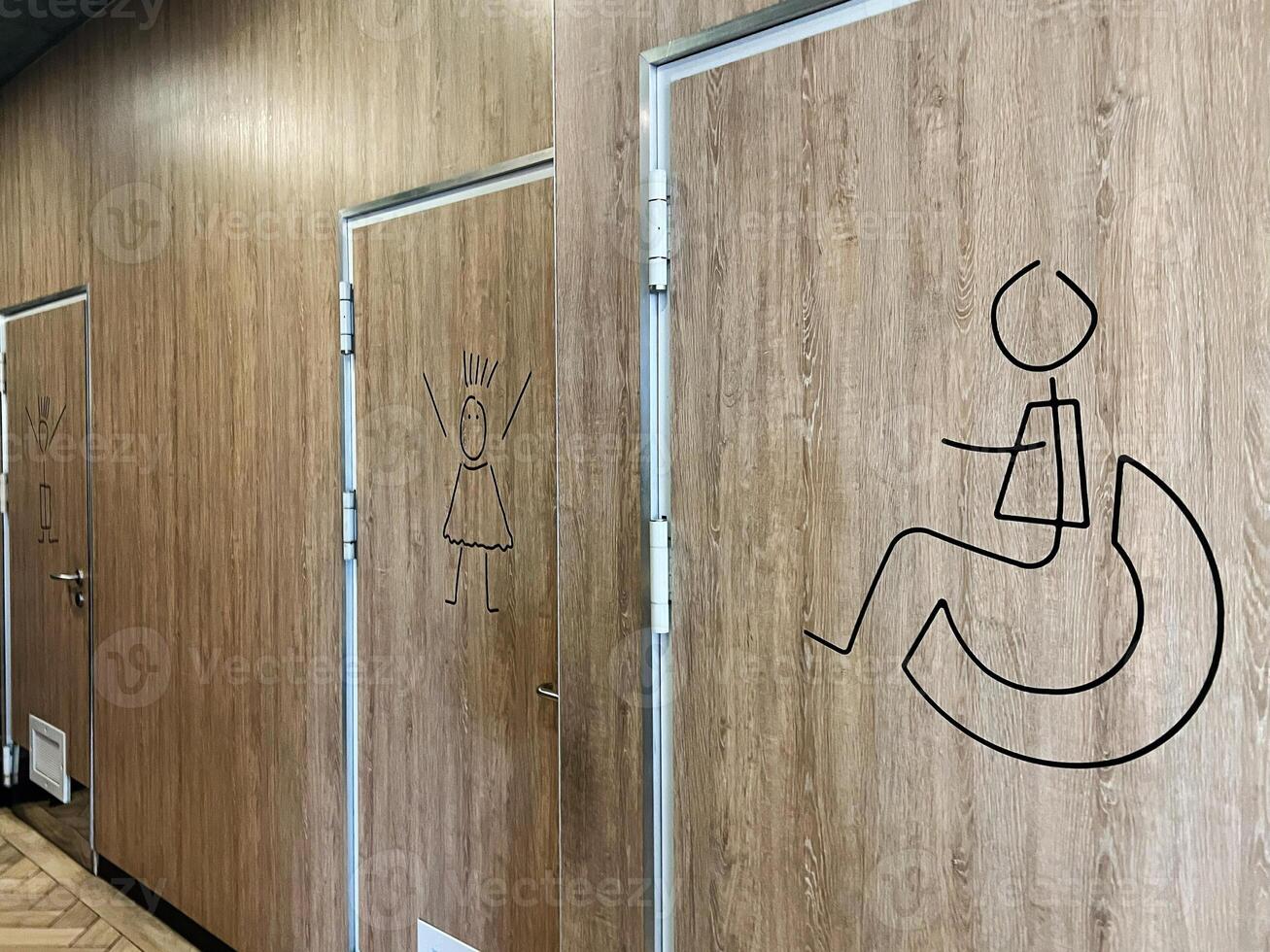 Accessible restroom doors marked with wood panel designs and cartoon symbols photo