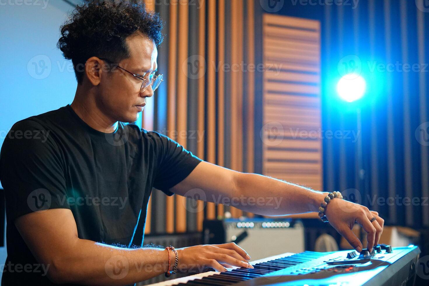 Musician playing music keyboard, Asian man in black shirt playing piano and practicing in home studio photo